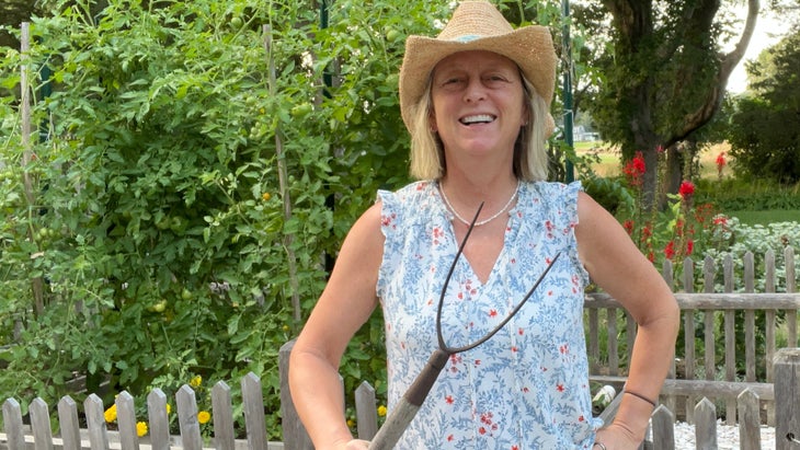 The author holding a garden tool in her garden