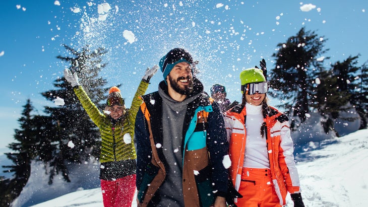 four friends throwing snow in air