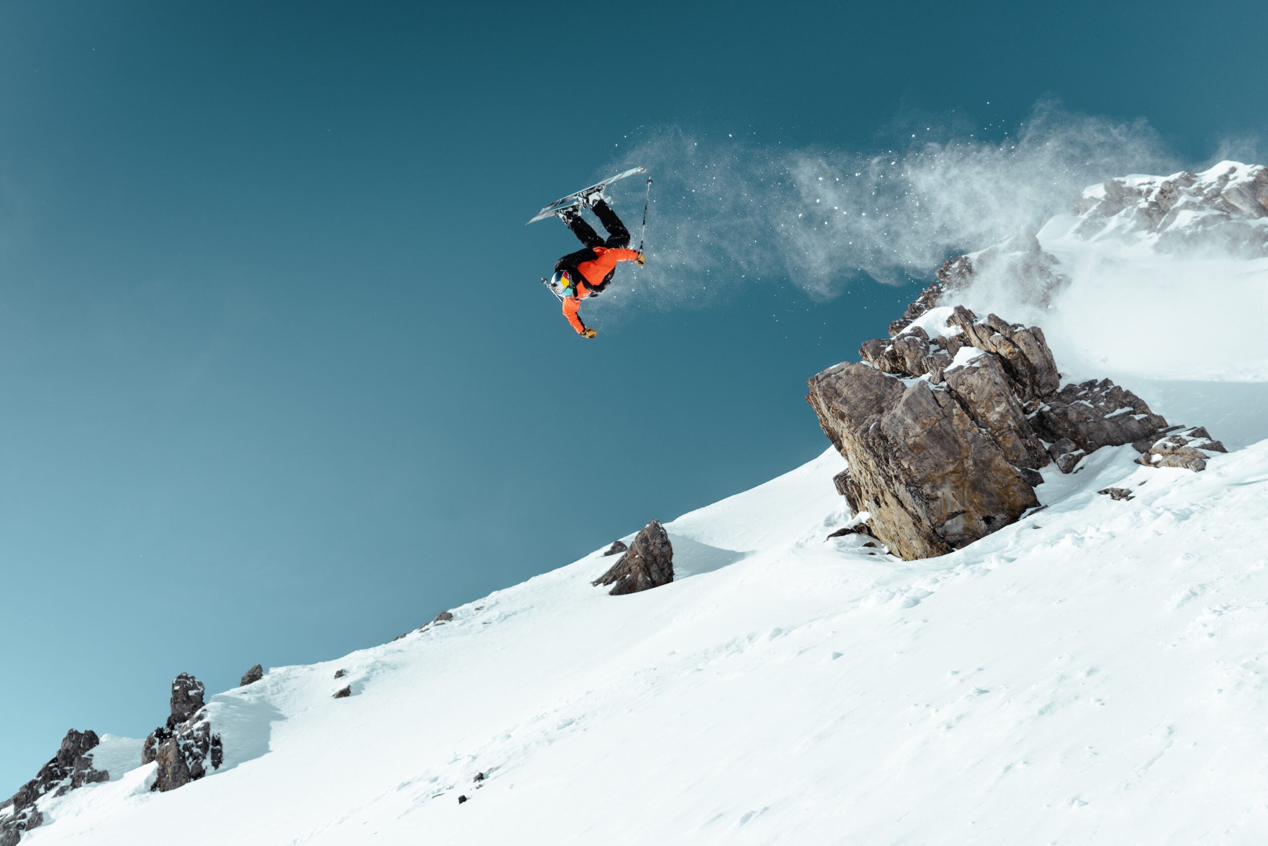 Skier mid air as he jumps off rock.