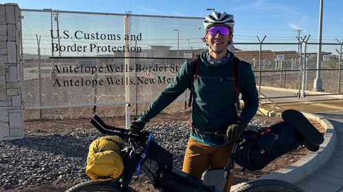 Man standing with mountain bike and U.S.-Mexico border