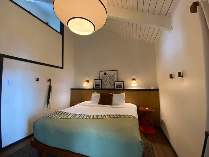 An interior shot of a queen bed and side tables at the Lodge at Marconi. 