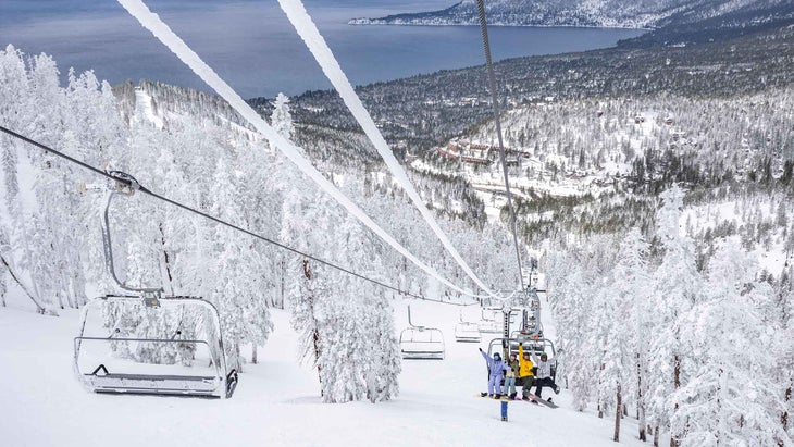 Three snowboarders riding a chairlift