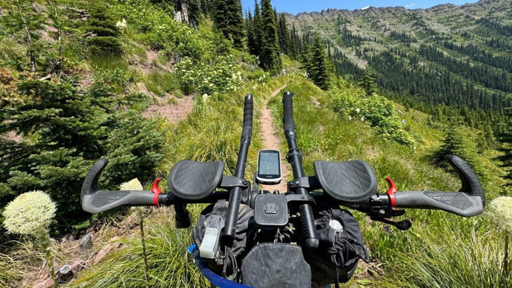 handlebars of mountain bike with navigation system on trail outside