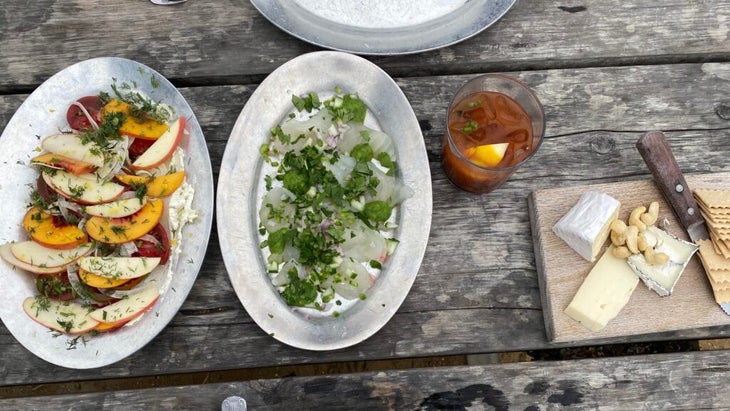 Lunch is set on a weathered wooden table at Northern California’s Hog Island Oyster Farm: a peach, tomato, and fennel dish, halibut ceviche, a Bloody Mary, and a platter of nuts and local cheeses.