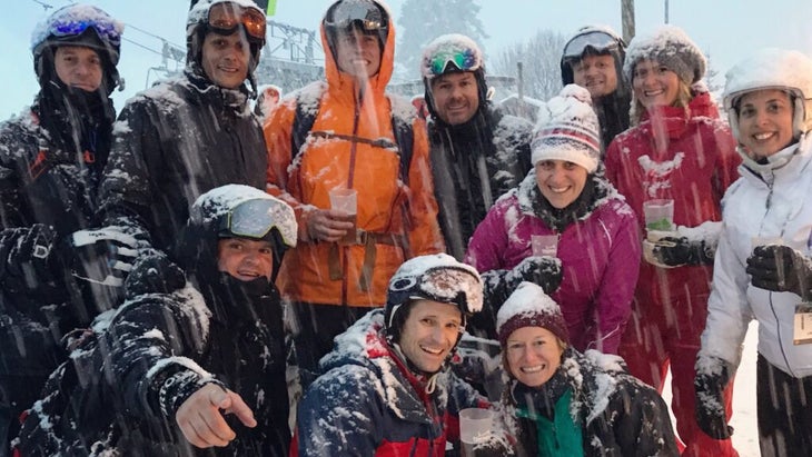 A group of skiers in France laughing during a heavy snowfall on the slopes.