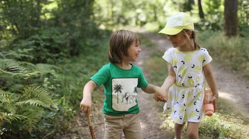 two kids holding hands on a trail