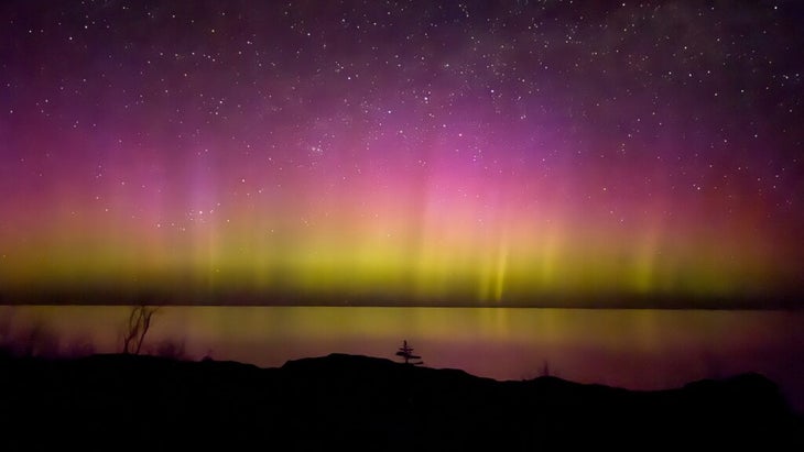 Purple, yellow and pink northern lights reflect off the surface of Lake Superior.