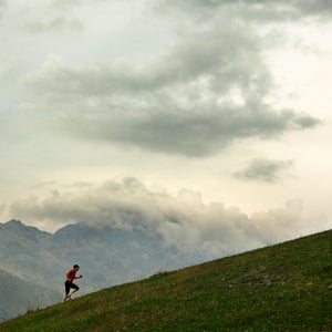 Man in red shirt and black shorts running uphill.