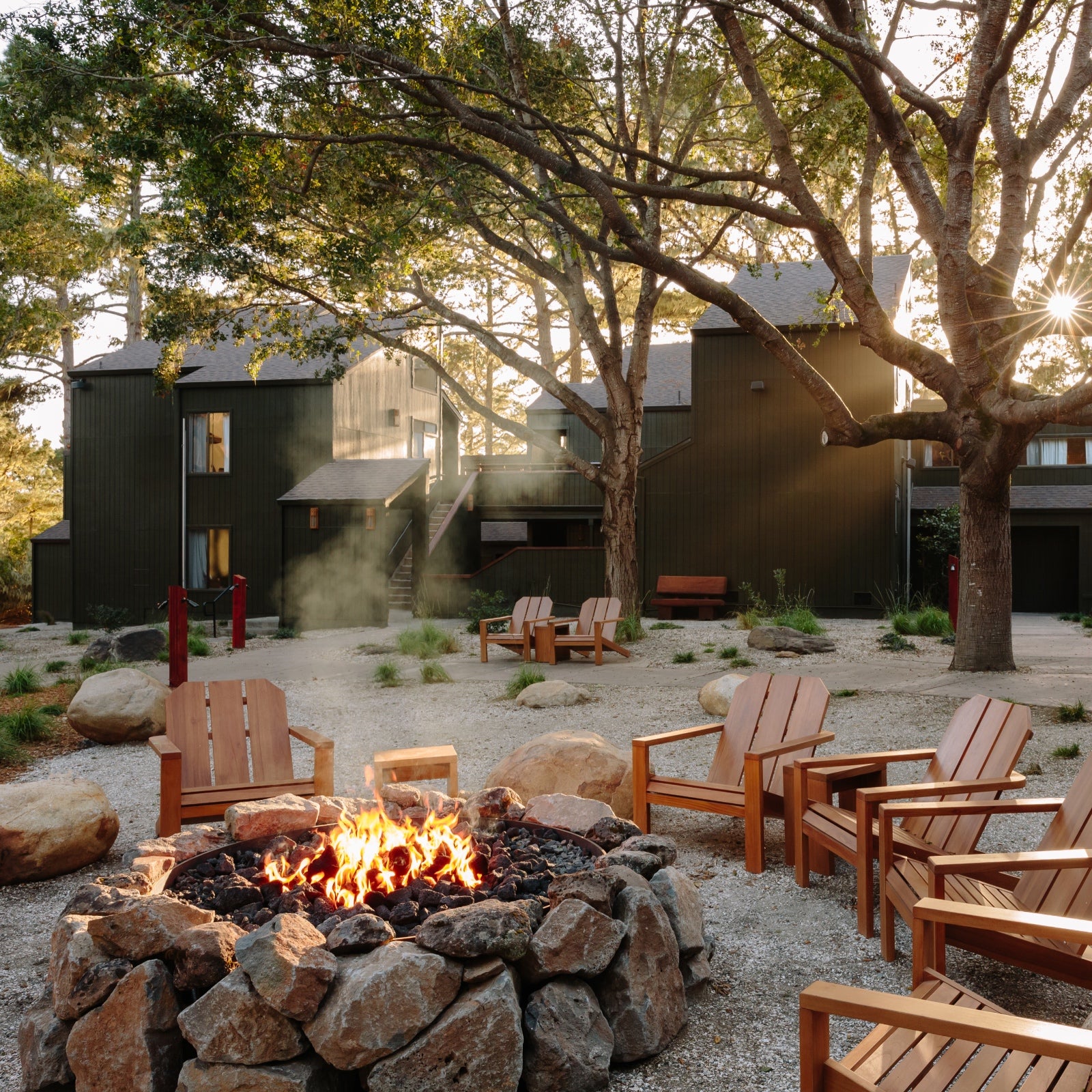 The lodge buildings set amid the forest and circling a central fire pit, surrounded by Adirondack chairs.