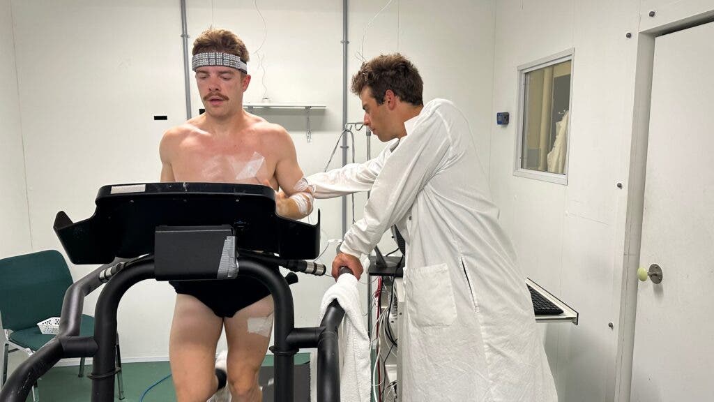 A test subject performs a treadmill exercise wearing an Omius cooling headband while a research monitors the exercise.