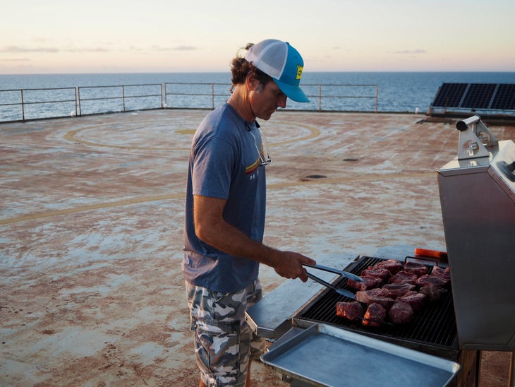 man grills steak on lighthouse