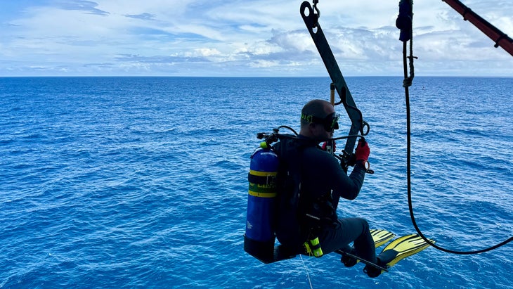 man lowered from a lighthouse to scuba dive