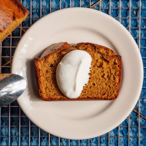 A slice of pumpkin bread topped with dollop of Greek yogurt.