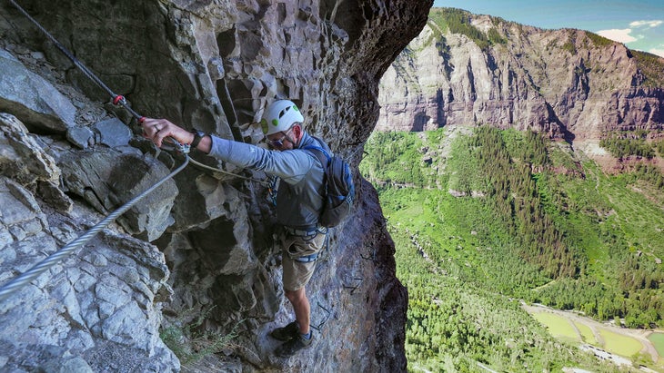 man climbing the telluride route, one of the higher via ferratas in the U.S., with the valley floor below