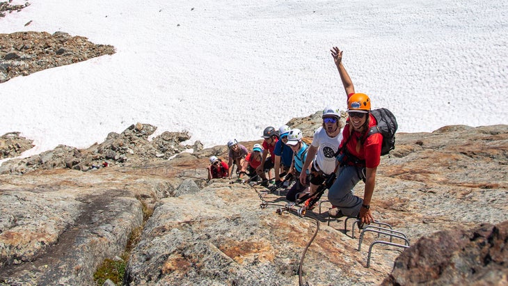 people climbing a ladder on whistler peak via ferrata in british columbia, canada