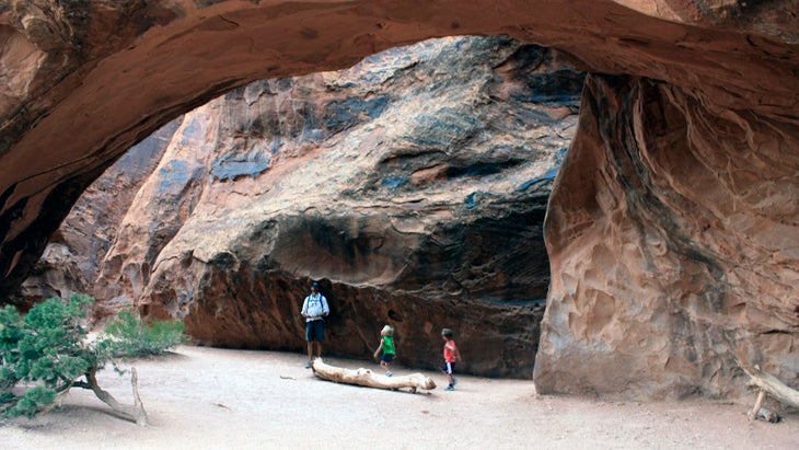 dad and two kids exploring an arch off of primitive loop in arches national park