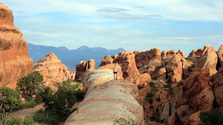 woman standing on sandstone outcroppings in arches national park, utah