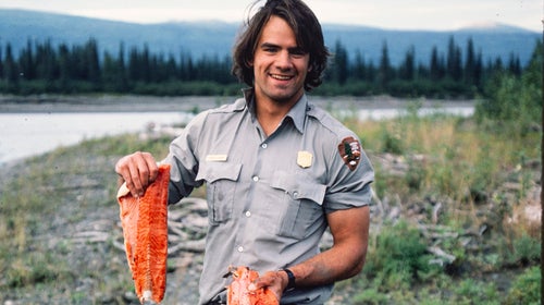 man in arctic holding up salmon filets