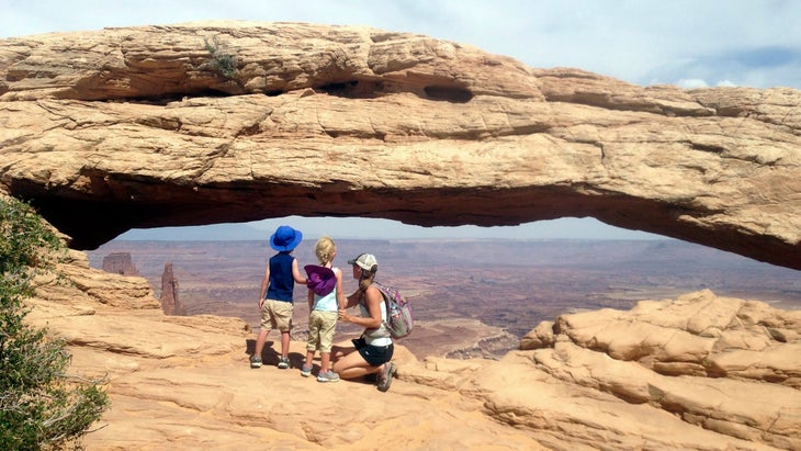 family enjoying the view through Mesa Arch in Canyonlands National Park