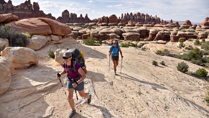 Two women backpacking on a trail through The Needles section in Canyonlands National Park, Utah