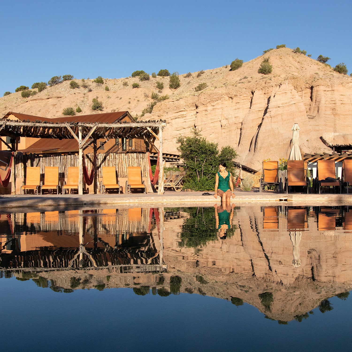 woman by pool and adobe buildings at hot springs resort in New Mexico