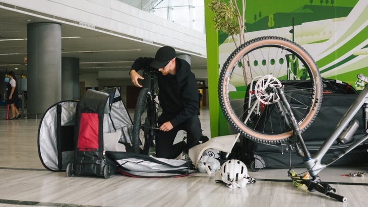 A man disassembles his bicycle to pack into a case for plane travel.