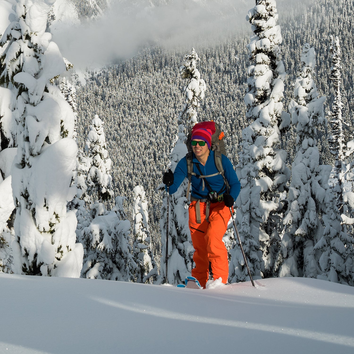 man skinning up snowy mountain slope