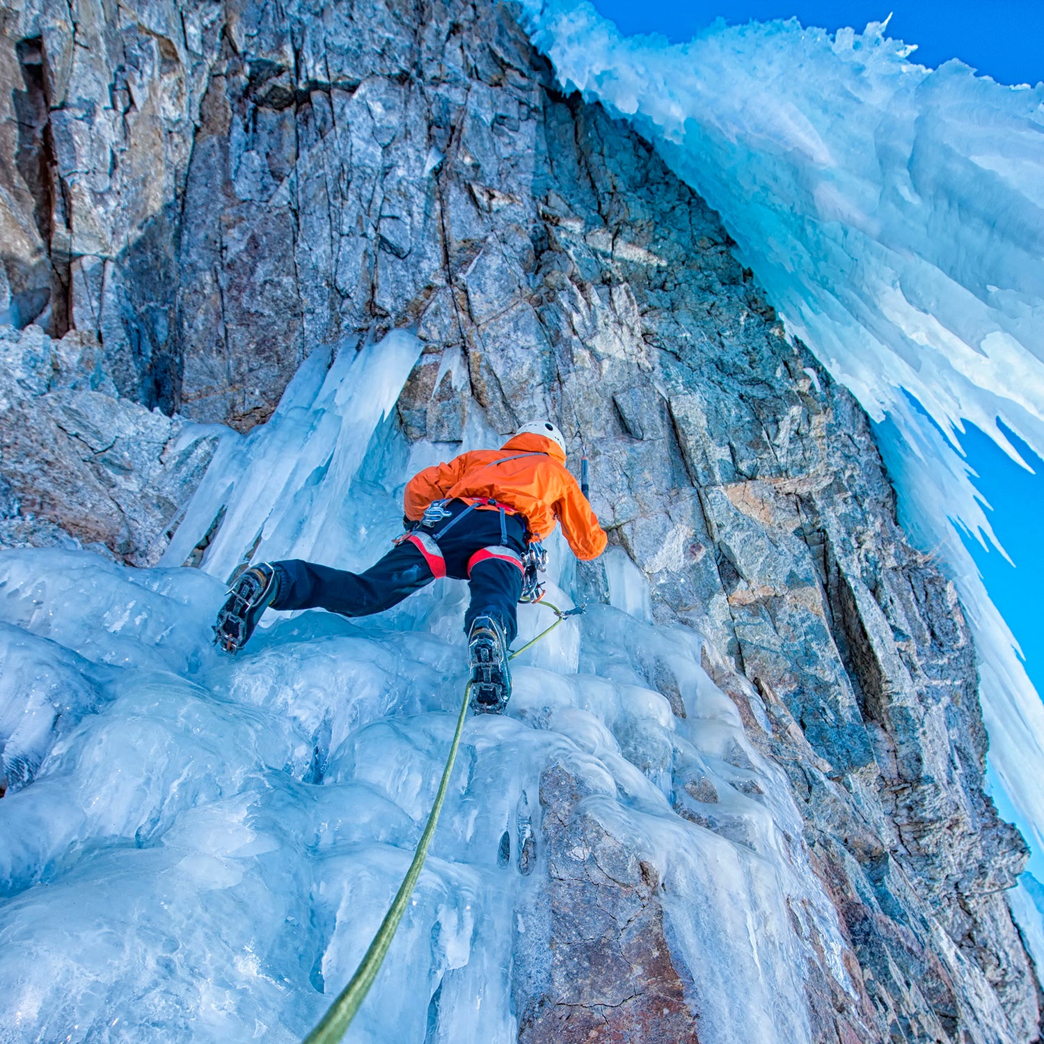 man ice climbing wearing layers