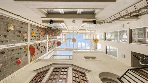 A vertical image of the world's tallest home climbing wall—which pierces a glass ceiling and keeps going.