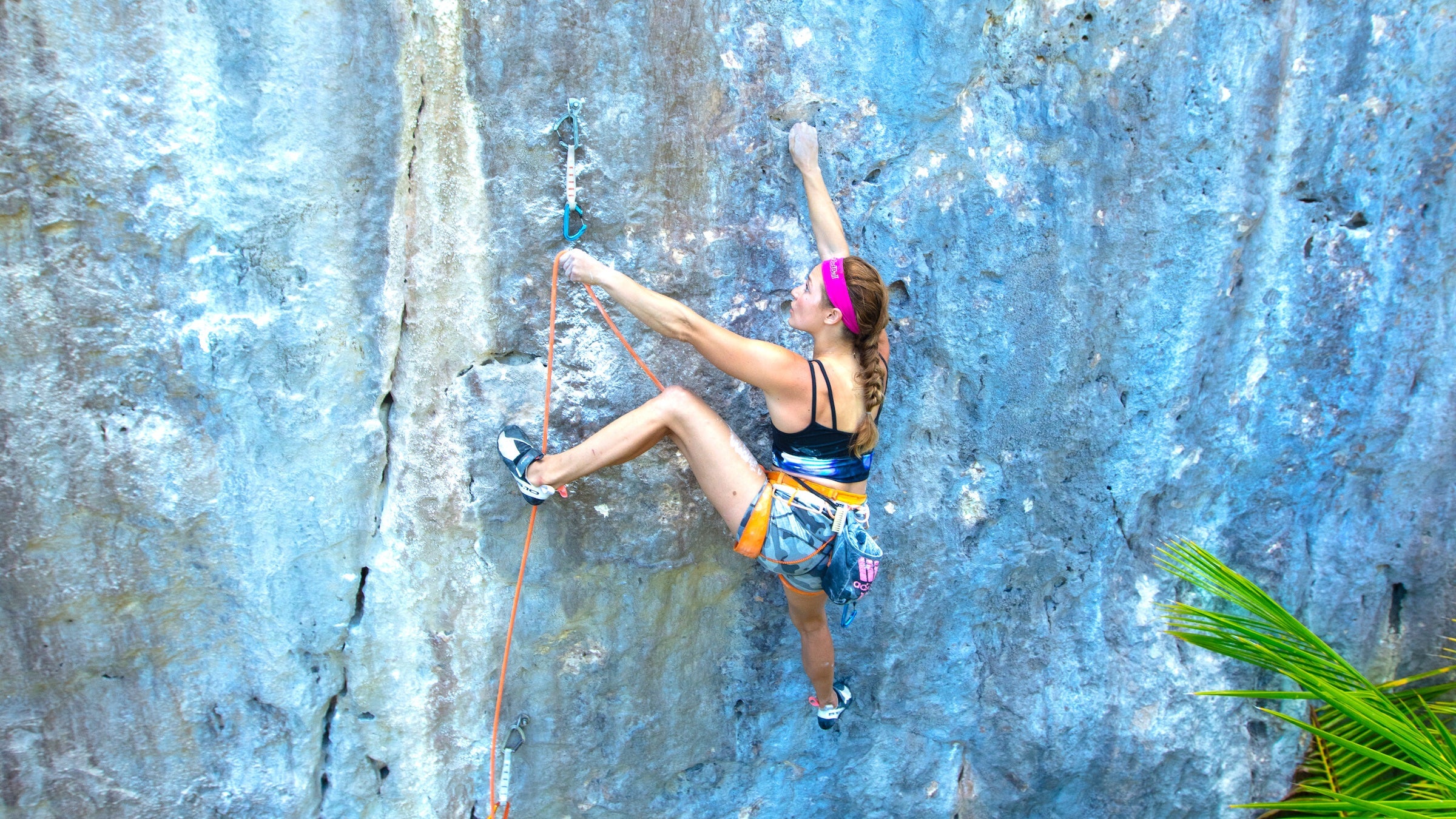 sasha climbing on outdoor rock, about to clip into a quickdraw