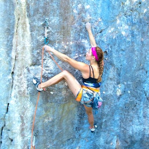 sasha climbing on outdoor rock, about to clip into a quickdraw
