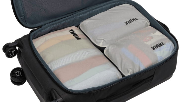 A carry-on suitcase filled with four white Thule packing cubes