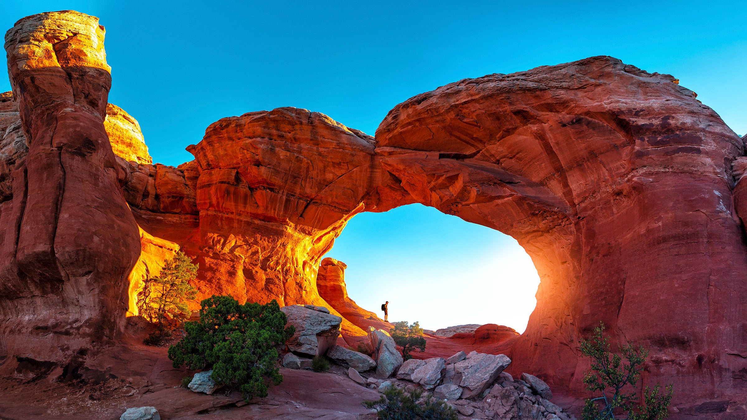 hiker watching sunrise in turret arch, arches national park, utah