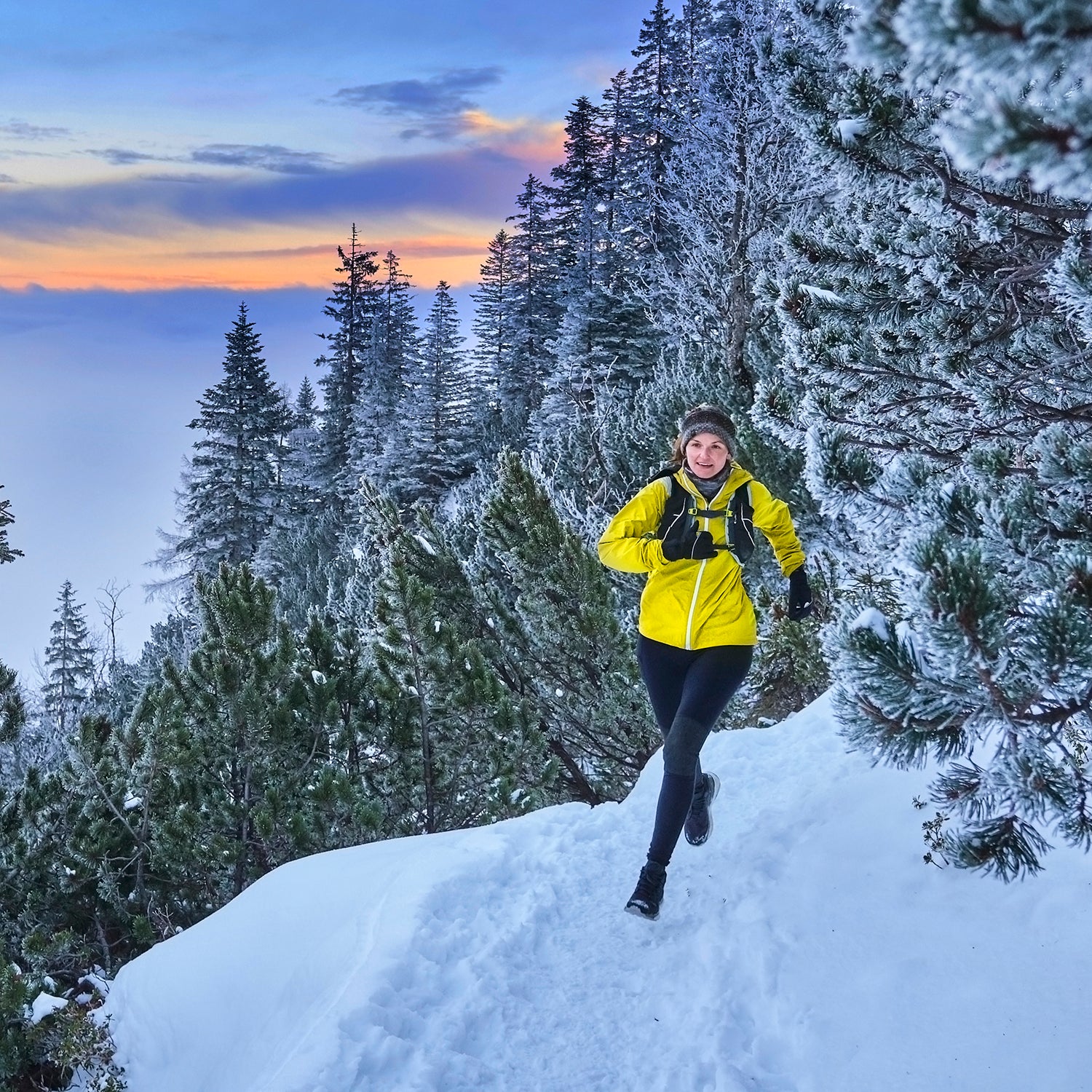 woman in fleece jacket running on snowy mountain trail