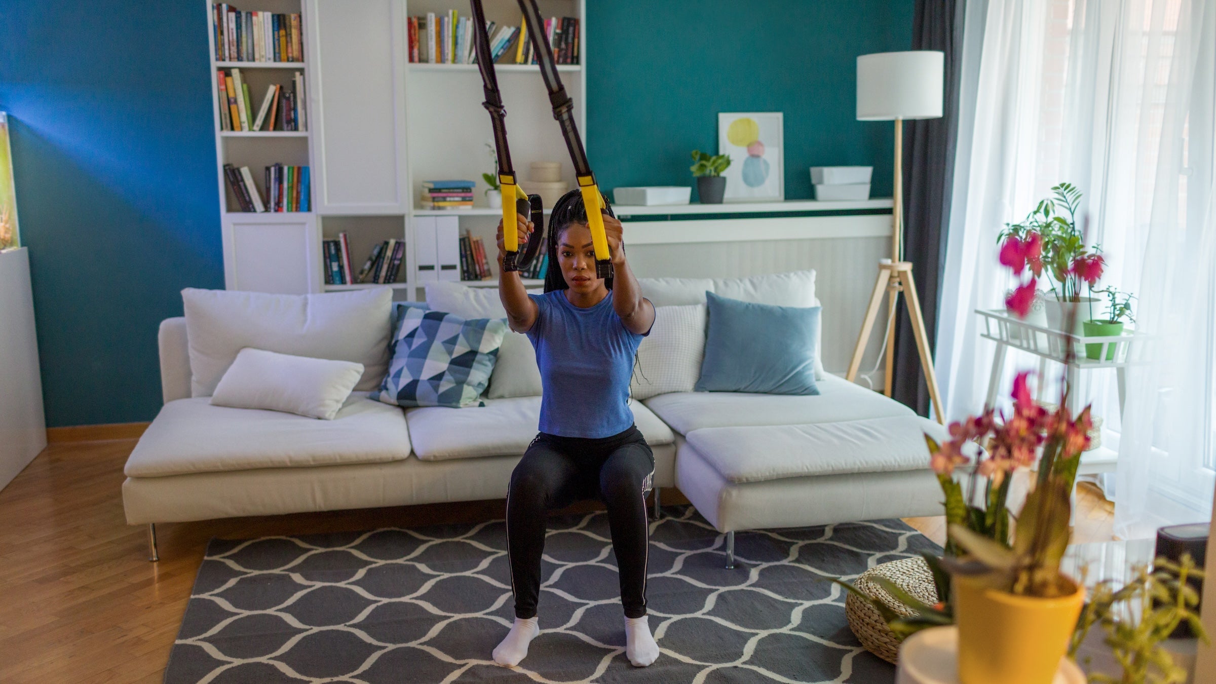 Young woman exercising at home with suspension straps