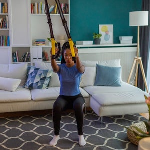 Young woman exercising at home with suspension straps