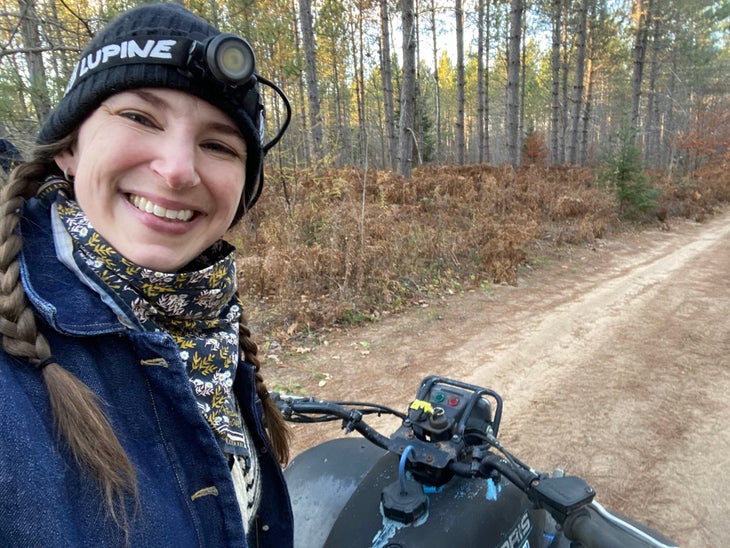 A selfie of Blair Braverman smiling while on her ATV in a wooded area