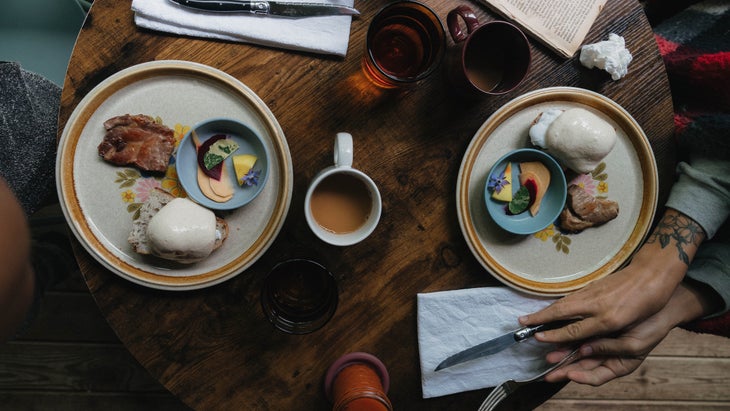 eggs, toast, meat, and fruit at a wooden table