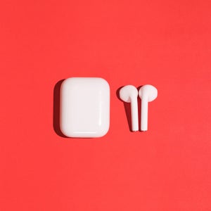 Trendy wireless white headphones earbuds on red background.