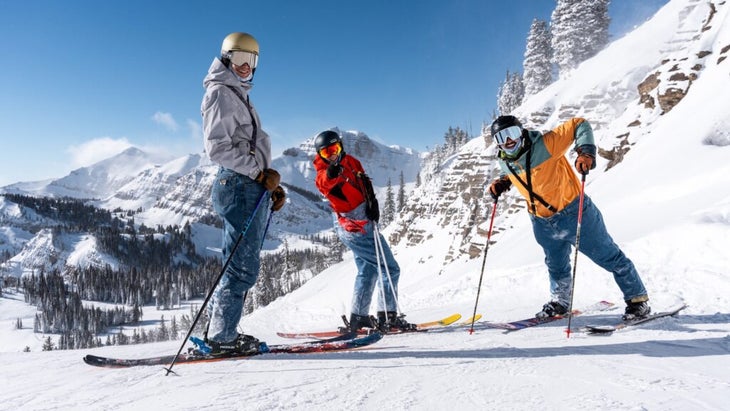 Three male skiers wearing jeans pose on a run at Jackson Hole Mountain Resort in Wyoming