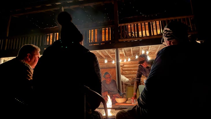 a group of people at night outdoors around a fire