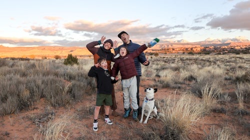 A family of four poses near Moab, Utah, with the family dog. Everyone is making funny faces.