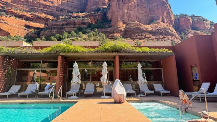 An older couple relaxes in the outdoor jacuzzi at the Enchantment Resort’s Mii Amo spa, with a soaring canyon wall in the background.