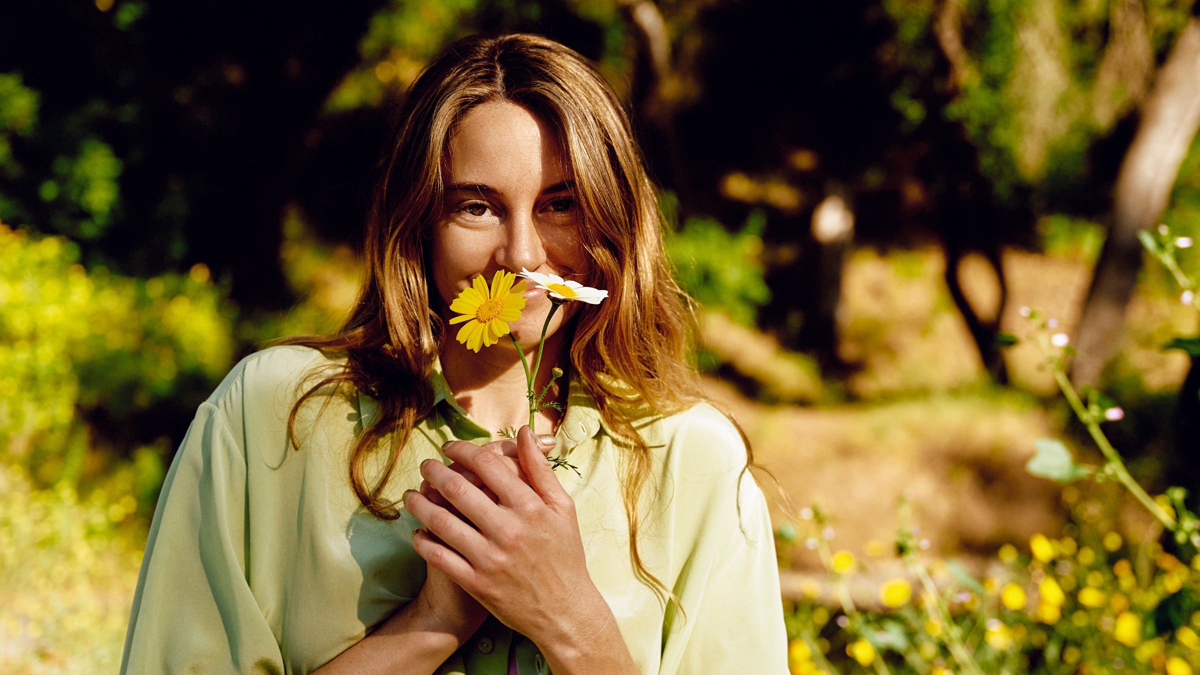 Shailene Woodley smelling flowers. Shirt by Olivia Von Halle