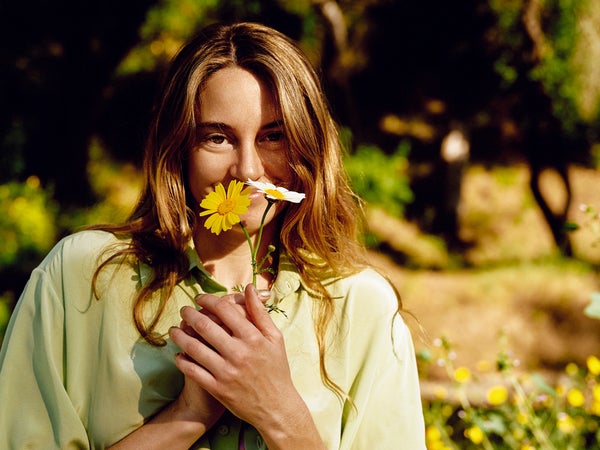 Shailene Woodley smelling flowers. Shirt by Olivia Von Halle