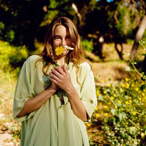 Shailene Woodley smelling flowers. Shirt by Olivia Von Halle
