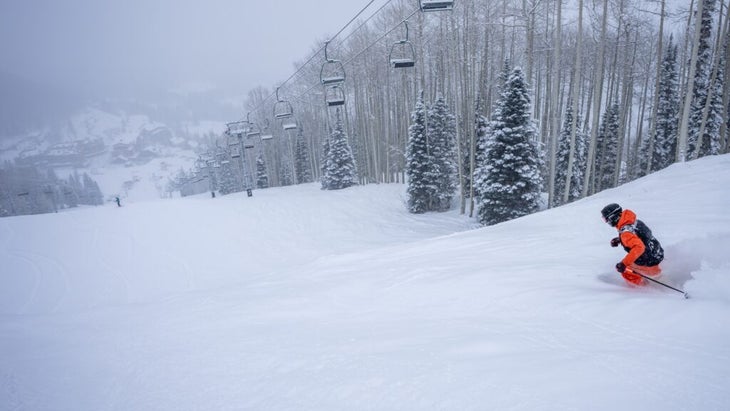 A skier wearing an orange jacket skies down an intermediate slope at Colorado’s Purgatory Ski Resort