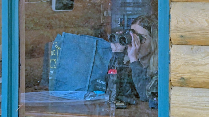 The author's wife using the Swarovski binoculars to spy wildlife out of a window.