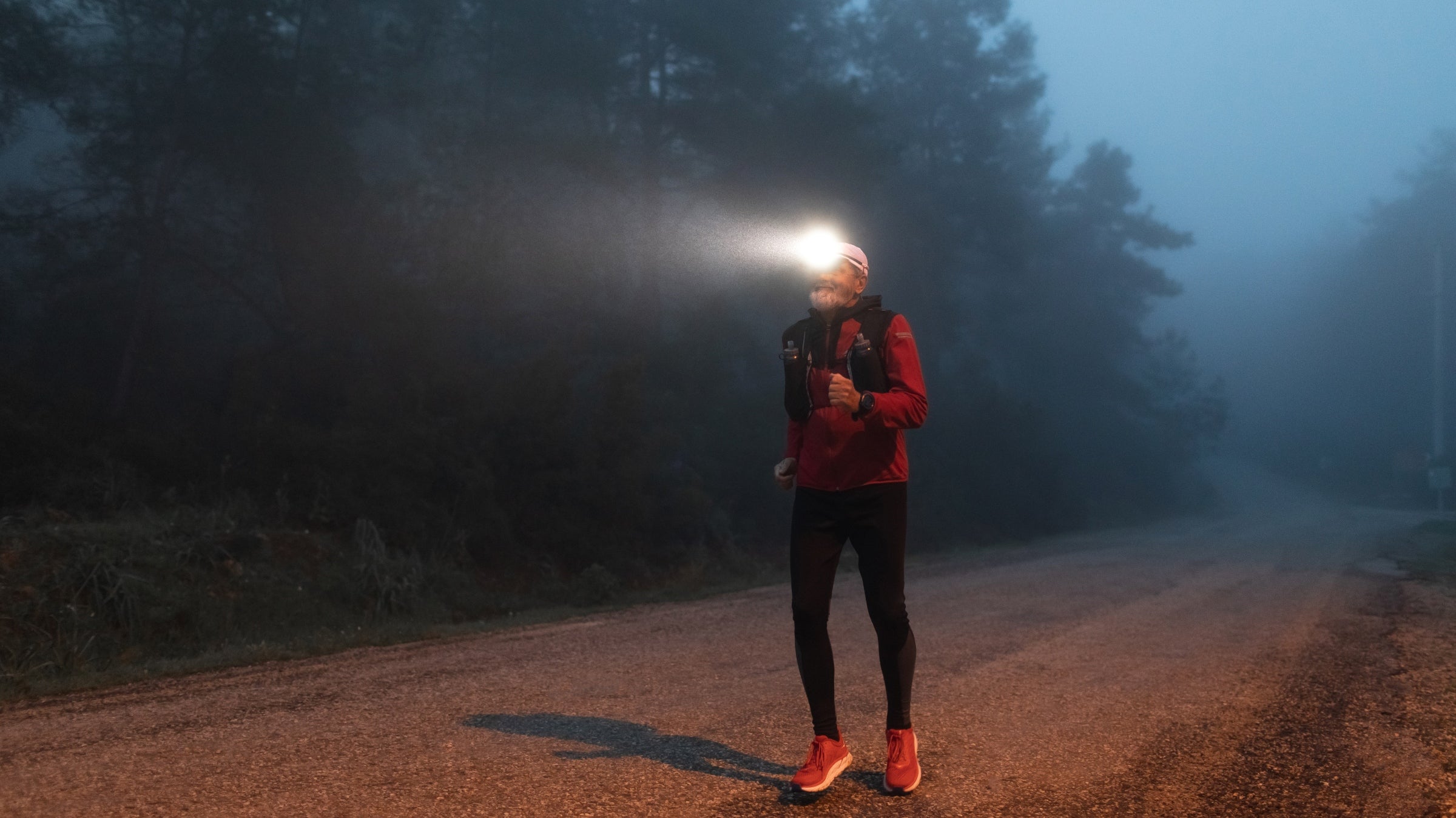 Man running a backyard ultra with headlamp in dark foggy weather