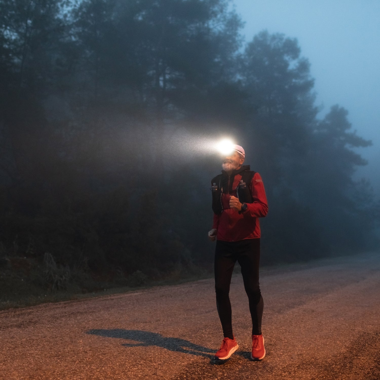 Man running a backyard ultra with headlamp in dark foggy weather